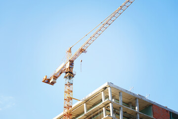 A tall crane is building a tall skyscraper to the very clouds