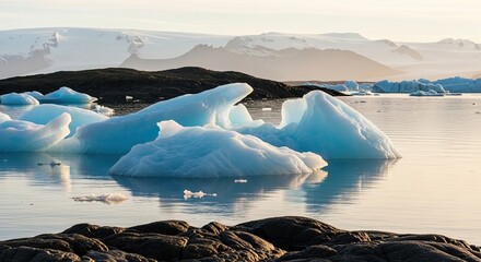 Majestic blue icebergs float serenely in a calm glacial lagoon during a beautiful sunrise, with a vast, snow-covered mountain range visible in the distant background