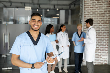 Cheerful middle-eastern young man in workwear doctor attending medical conference, holding chart...