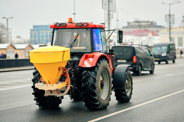 Salt spreading tractor. Winter maintenance tractor spreading salt mixture along city road to improve traction and prevent accidents caused by snow and ice accumulation, urban road deicing operation © Tricky Shark