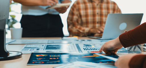 A dynamic office environment showcases a diverse team collaborating on project planning. Charts and laptops dominate the workspace, fostering creativity and innovation. SACTR