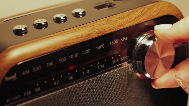 Tuning an analog radio station frequency. Hand turns the tuning knob, adjusting indicator while scanning various radio frequencies. High quality 4k footage