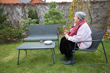 Cozy autumn garden moment with woman relaxing outdoors in casual attire
