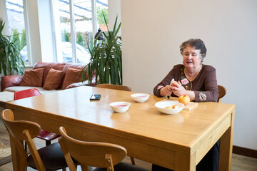 Woman peeling apple at dining table in cozy home interior with plants