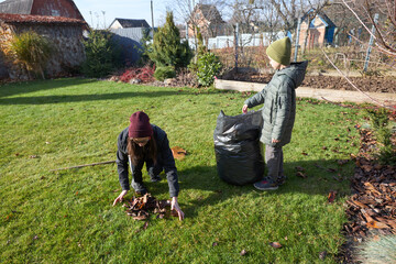 Autumn garden cleanup: family raking leaves together outdoors