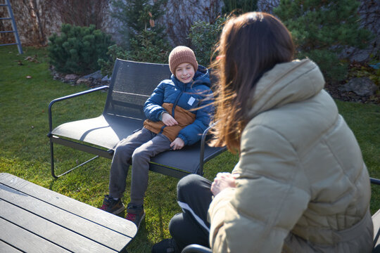 Outdoor winter chat: mother and son enjoying sunny day in the garden