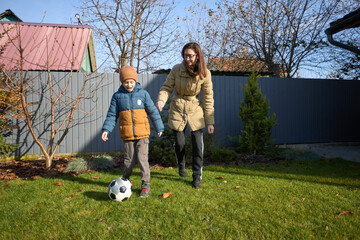 Mother and son enjoy a soccer game in autumn backyard scene