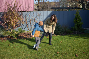 Mother and child play soccer in autumn garden