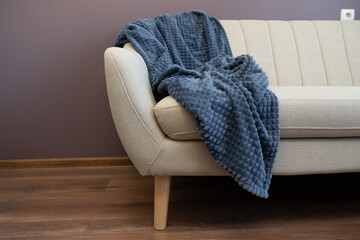 Cozy beige sofa with a textured blanket draped gently, creating a soft and inviting relaxation spot.