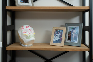Home shelf with framed photos, sugar skull and small potted cacti, evoking a cozy and personal interior mood.