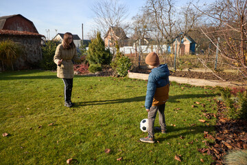Autumn backyard soccer game: mother and child enjoy playful moments outdoors