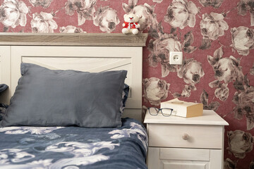 Cozy bedroom detail with pillow, book and glasses on a nightstand, evoking a quiet and intimate evening mood.