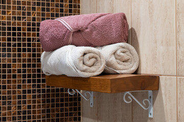 Softly lit bathroom shelf with folded towels, combining texture and warmth in a clean, inviting space.