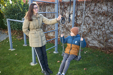 Autumn playground fun with mother and son on swing