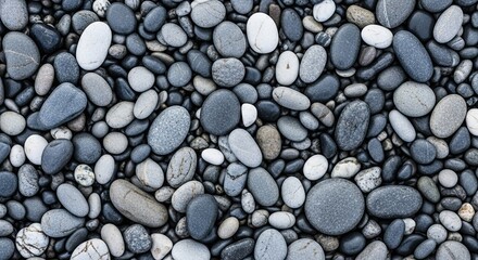 Overhead flat lay of a collection of smooth, rounded stones in a monochromatic palette of grey and white, forming a peaceful and textured natural pattern