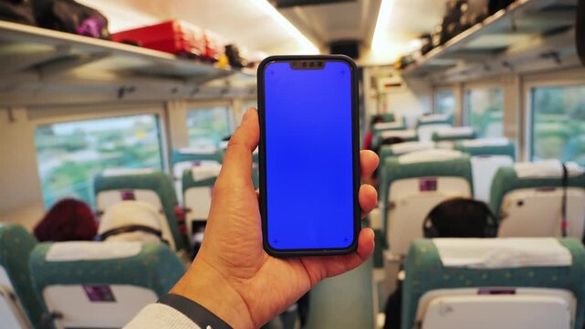 Man traveler in high speed train using smartphone with blue screen chroma key, using mobile apps, social media, watching video content. High quality 4k footage