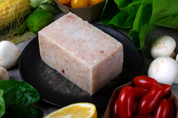 Frozen portioned minced white fish on a ceramic plate surrounded by ingredients for making healthy...