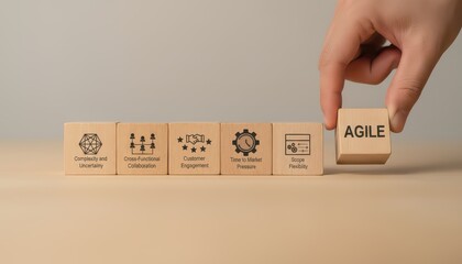 Hand placing agile wooden block in a row of process icons on table