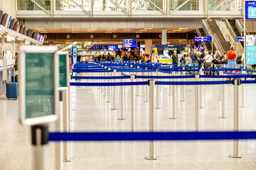 Metallic barrier poles with blue retractable belts in a row located in an airport terminal