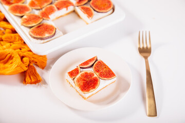 A delicious slice of fig and cream cheesecake on a white plate, topped with fresh fig slices