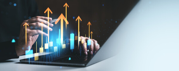 Business growth concept with upward arrows and candlestick chart graphics overlaying hands typing on laptop in creative digital background.