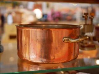 Copper cooking pot displayed on a kitchen store counter, shiny red-copper metal cookware suitable for professional or home cooking, classic pot shape ideal for culinary equipment catalogs and retail