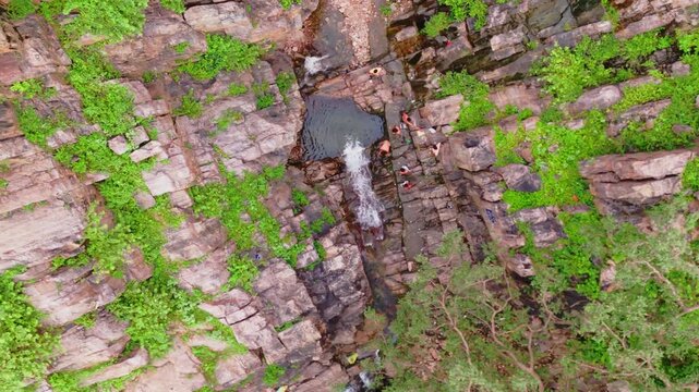 view shot of Garbhaji Falls in Alwar, Rajasthan, where four people are bathing under the fresh waterfall stream. 