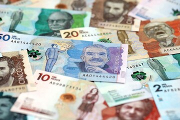 Colombian pesos money bills banknotes lies in big pile on table close up. Concept of finances and...