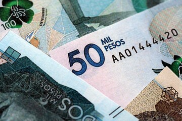 Colombian pesos money bills banknotes lies in big pile on table close up. Concept of finances and...