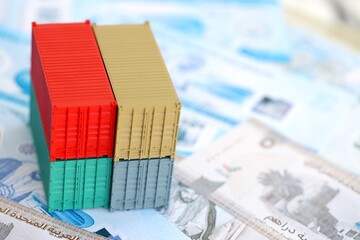 United Arab Emirates dirham currency money bills and toy cargo containers close up. The concept of shipping and logistics