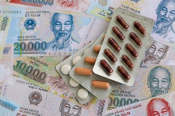 Vietnamese dong currency money bills and medicine pills close up. The concept of medicine and...