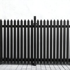 A black, pointed-top picket fence with a gate stands against a white wall. The ground is paved with rectangular tiles
