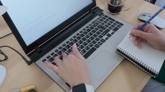 Writer or creator drafting ideas in a notebook before typing on a laptop.