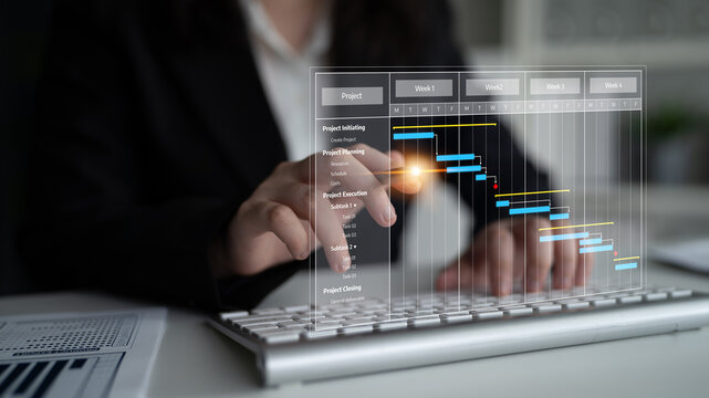A focused businesswoman analyzes project management data using a Gantt chart on her computer keyboard in a modern office, enhancing productivity and organization. Tessel