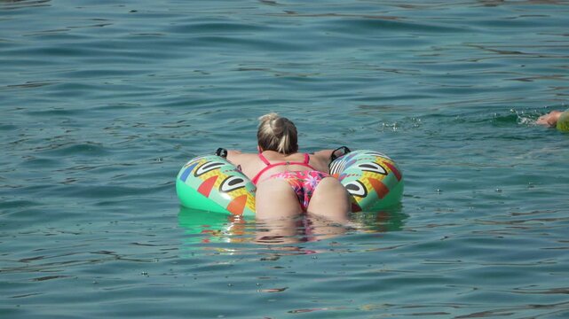 Woman floating sea, relaxing on inflatable ring in blue water during summer vacation.