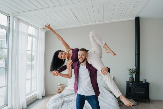 A playful moment captured as a couple dances joyously in a bright room, expressing happiness and connection.