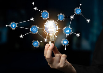 A dynamic representation of innovation and technology featuring a hand holding a light bulb, symbolizing ideas connected through digital icons in a network. Crux