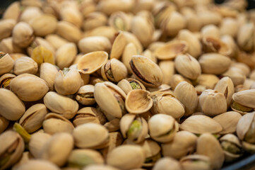 A pile of fresh pistachios in shells, some open revealing the green kernel. A healthy, delicious snack, a source of energy and beneficial fats, selective focus