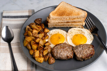 fried eggs served with breakfast  sausage patties and home fries