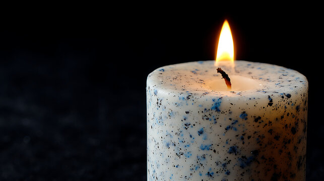 Speckled white candle with bright flame burning light