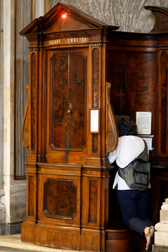 Santa Maria Maggiore Basilica.  Baroque confessional with Italian and English signs, worshipper kneeling for sacramental reconciliation inside church.pŽnitent,