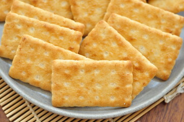 A close-up shot of several rectangular, light brown crackers stacked neatly on a speckled gray plate.