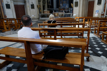 Basilica Santa Maria in Montesanto.  Devout people seated in wooden pews, quiet contemplation and solitude.