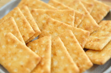 A close-up shot of several rectangular, light brown crackers stacked neatly on a speckled gray plate.