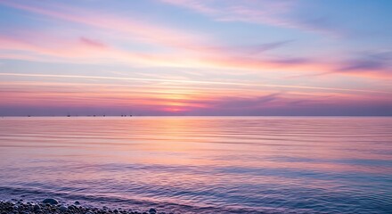 Pastel colored sunset over a calm and tranquil ocean horizon.