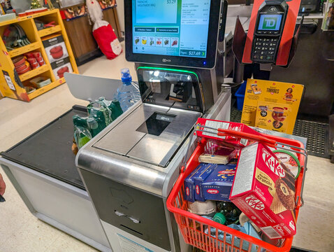 Canada, 05 November 2025 : Self checkout machine scanning groceries and snacks with payment terminal nearby
