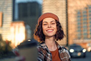 Fototapeta premium Woman smile coffee urban portrait, candid lifestyle capture at golden hour glow with authenticity and mindful living, emotional storytelling in a warm modern city scene.