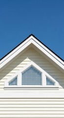 Obraz premium Gable of a house with triangular window against a clear blue sky