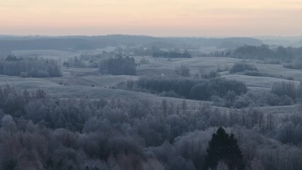 Panoramic view of frosted hills and forests under a warm sunrise sky, capturing the peaceful stillness of a rural winter landscape. - Powered by Adobe