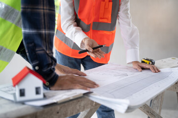 Concept Teamwork of building construction staff. Project engineer contractor reviewing plan of work with foreman and worker at construction site.